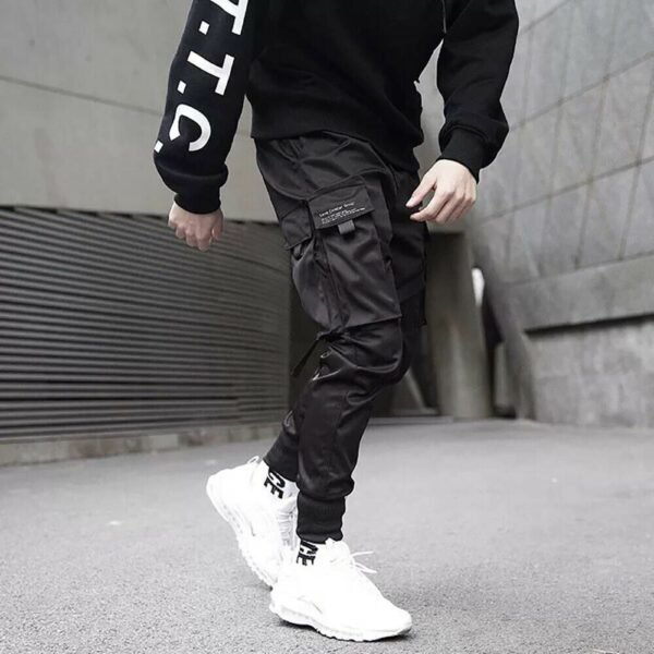 Man in techwear jogger pants stepping forwards